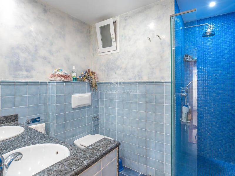 Salle de bain avec carrelage bleu, double vasque en granit et douche en mosaïque bleue.