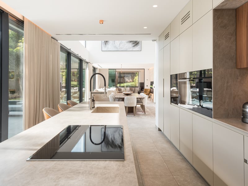 Cuisine moderne avec un grand îlot en pierre, des appareils intégrés et des baies vitrées donnant sur une piscine.