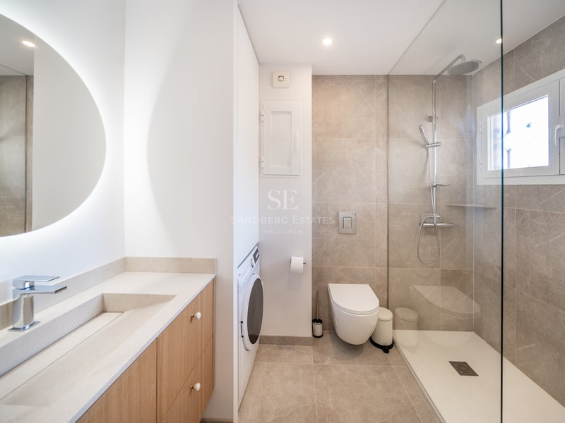 Salle de bains contemporaine avec douche à l'italienne, meuble en chêne clair et lave-linge intégré.