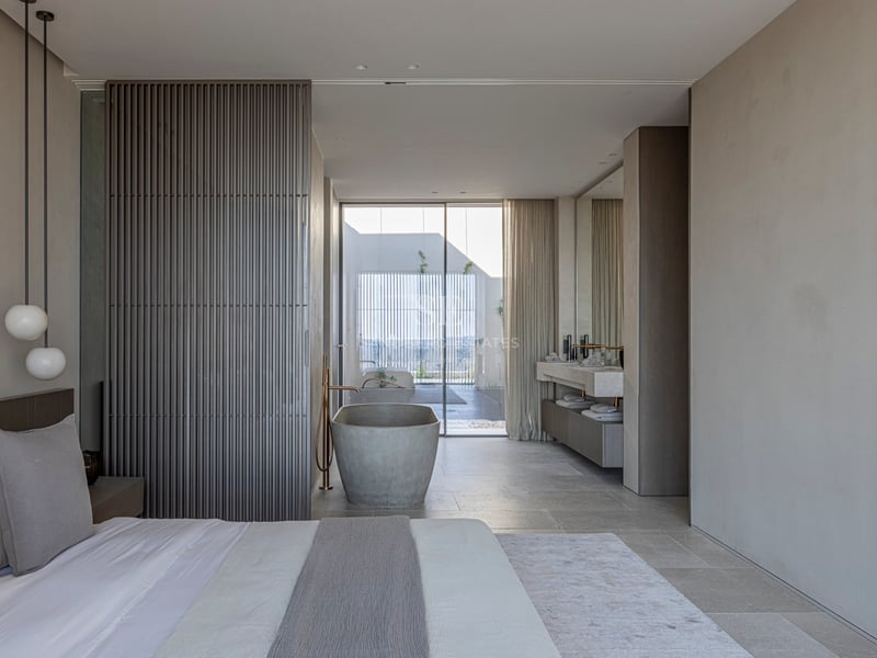 Chambre moderne avec baignoire en pierre îlot, panneaux en bois et baies vitrées toute hauteur.