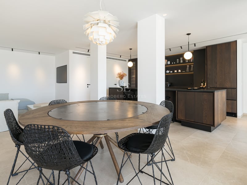 Table à manger ronde en bois avec chaises tressées noires dans un espace de vie moderne ouvert.