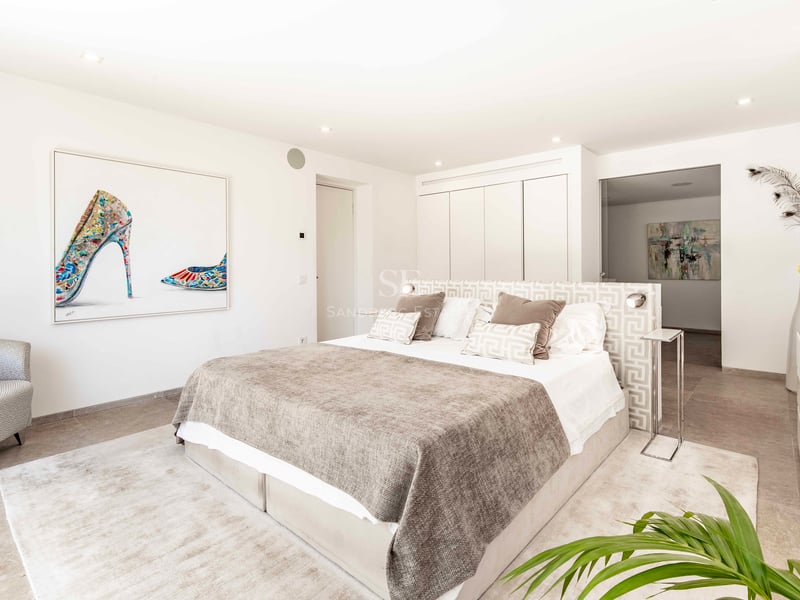 Chambre moderne et lumineuse avec lit king-size, tons neutres, armoires encastrées et art contemporain grand format.
