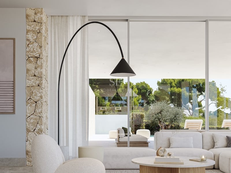 Salon lumineux avec mobilier bouclé, mur en pierre naturelle et baies vitrées ouvrant sur le jardin.