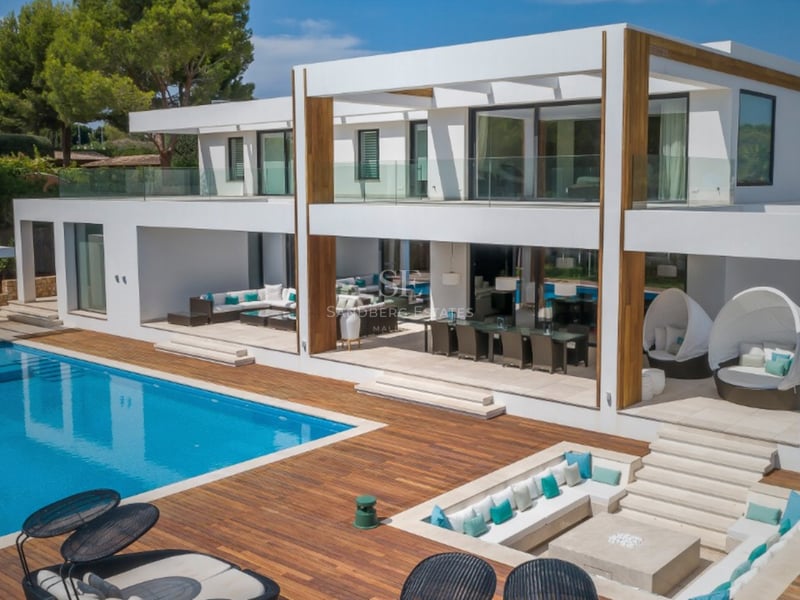 Villa contemporaine blanche avec grande piscine, terrasse en bois et salon extérieur encastré.