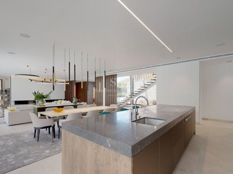 Cuisine contemporaine avec îlot en pierre grise, meubles en bois et coin repas avec luminaires design.