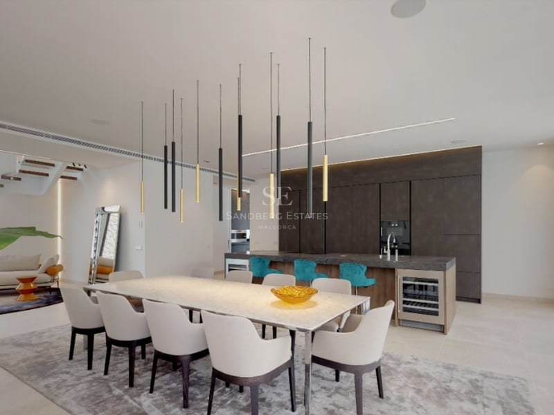 Salle à manger spacieuse avec une longue table blanche, des suspensions design et un îlot de cuisine avec tabourets turquoise.