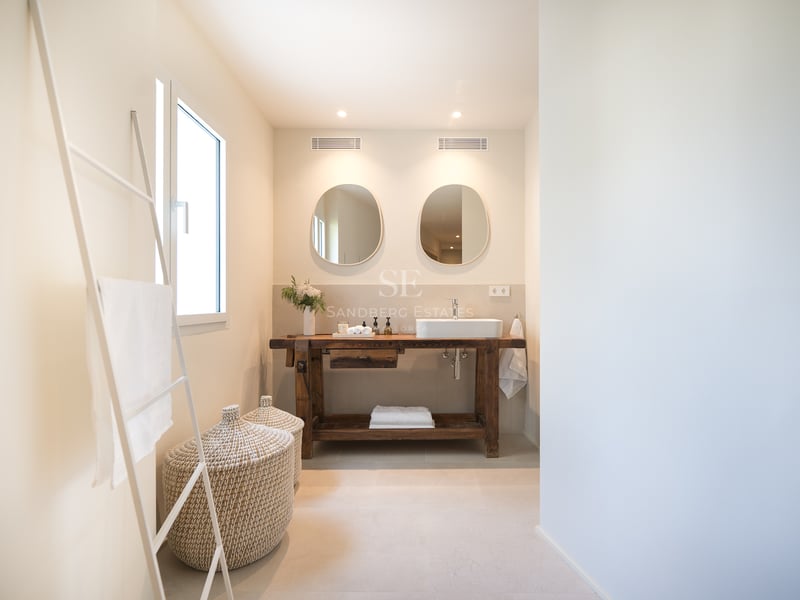 Salle de bains moderne avec meuble en bois de récupération, vasque à poser, miroirs organiques et paniers en osier.