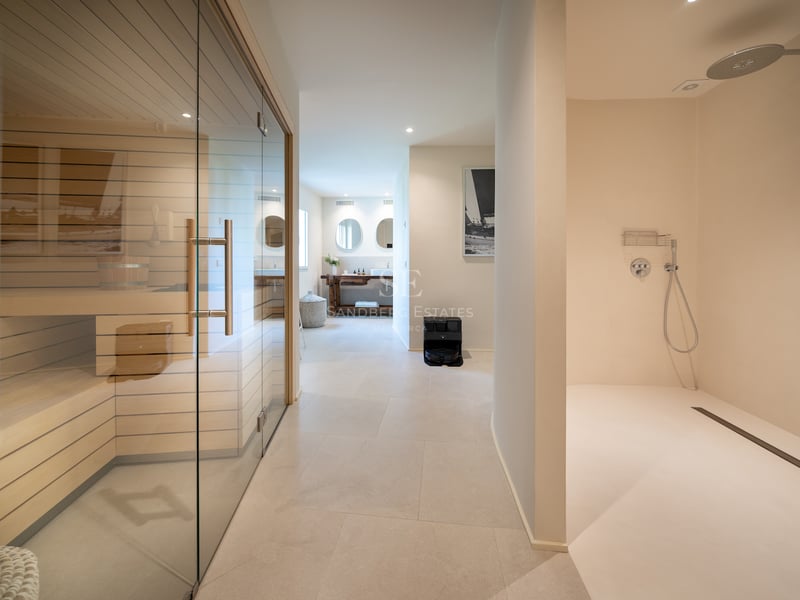 Espace spa intérieur comprenant un sauna vitré, une douche à l'italienne et des sols en pierre claire.
