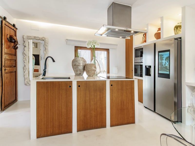 Cuisine contemporaine avec îlot en bois, plans de travail blancs et réfrigérateur intelligent en inox.