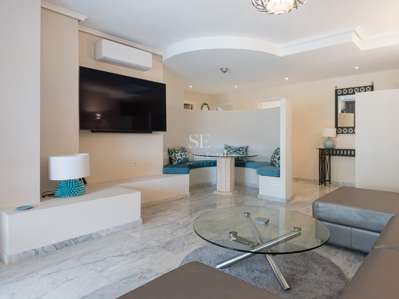 Salon moderne avec sol en marbre, canapé en cuir et un coin petit-déjeuner incurvé avec coussins turquoise.