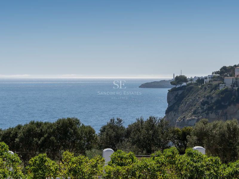 Vue sur la côte avec des maisons blanches sur une falaise et la mer bleue sous un ciel clair.
