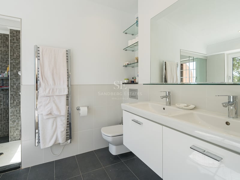 Salle de bain moderne avec double vasque blanche, grand miroir, sèche-serviettes et douche à l'italienne.