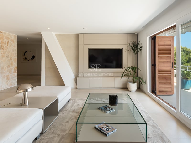 Salon contemporain lumineux avec canapés blancs, table en verre et grandes baies vitrées ouvrant sur la mer Méditerranée.