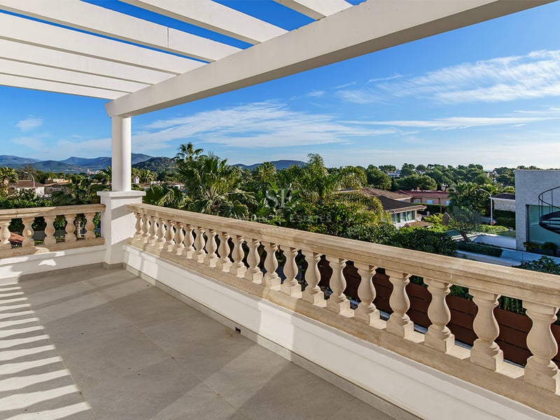 Grande terrasse avec pergola blanche, balustrade en pierre sculptée et vue sur la végétation tropicale et les montagnes.