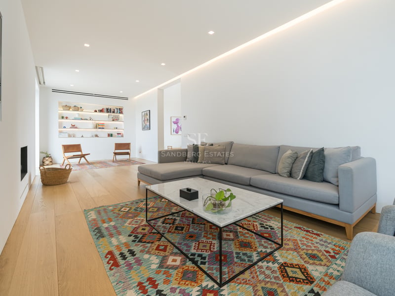 Salon moderne spacieux avec canapé d'angle gris, table en marbre et parquet en chêne clair.