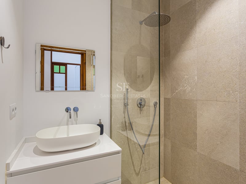Salle de bain moderne avec une vasque blanche et une douche à l'italienne avec des carreaux en pierre beige.
