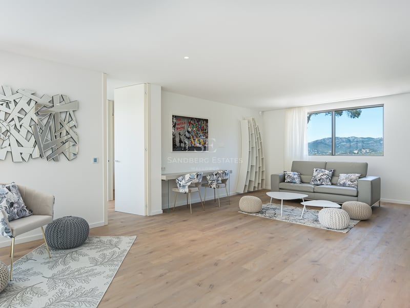 Salon contemporain lumineux avec parquet en chêne, canapé gris et fenêtre cadrant un paysage montagneux.