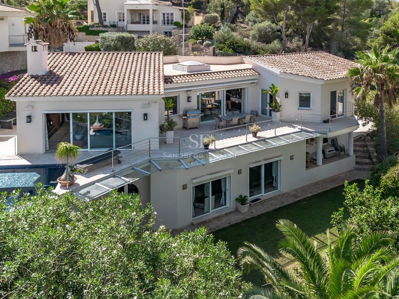 Vue aérienne d'une villa blanche à toit de tuiles, garde-corps en verre, grandes terrasses et piscine privée.