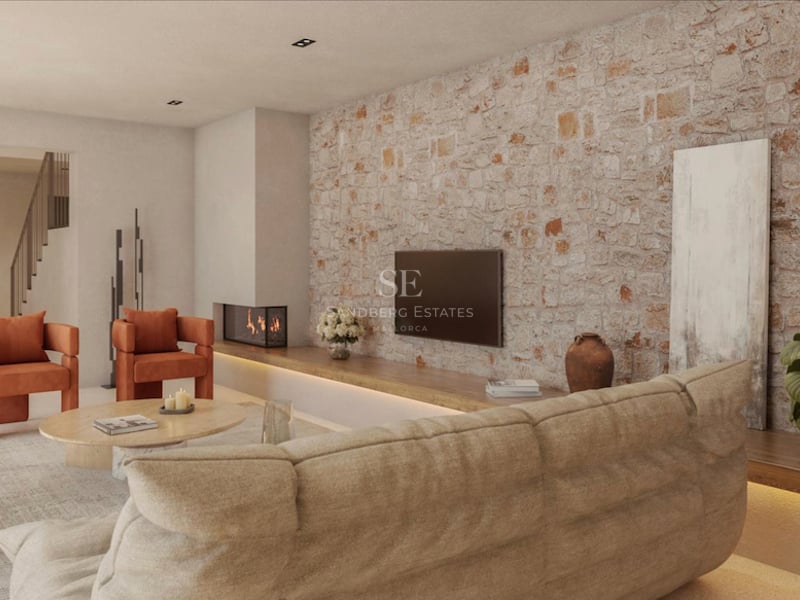 Salon moderne avec mur en pierre apparente, fauteuils orange, canapé beige et cheminée intégrée.