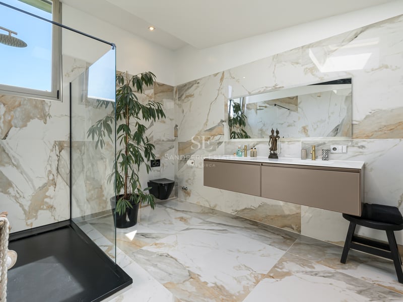 Salle de bain de luxe avec murs en marbre, douche à l'italienne et double vasque suspendue.
