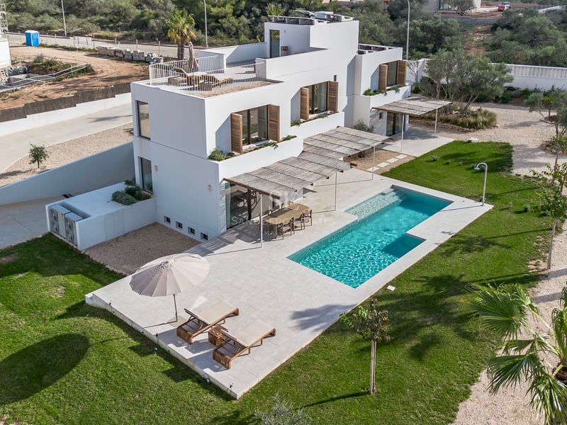 Vue aérienne d'une villa contemporaine blanche sur deux étages avec piscine, terrasse en pierre et pelouse.