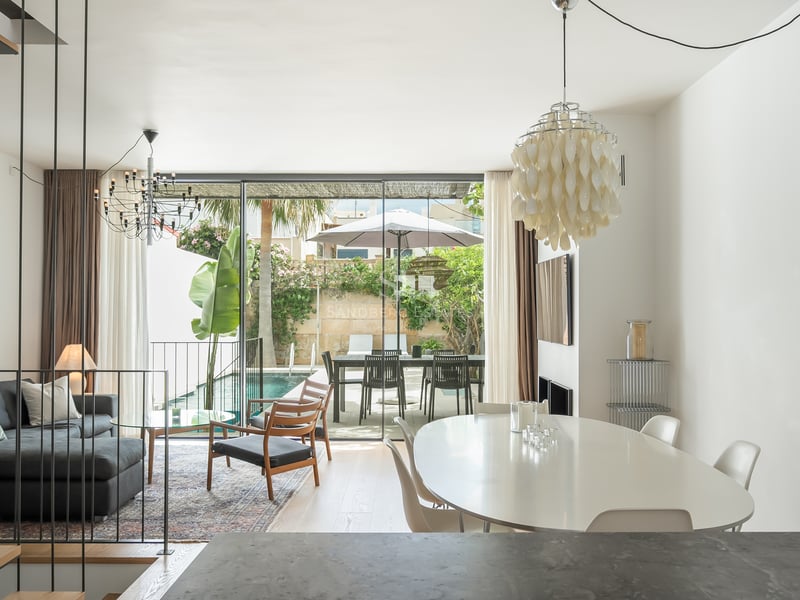 Salon et salle à manger lumineux avec baies vitrées s'ouvrant sur une piscine privée et une terrasse.