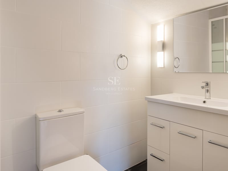 Salle de bain moderne avec carrelage blanc, meuble sous-vasque à tiroirs et robinetterie chromée.