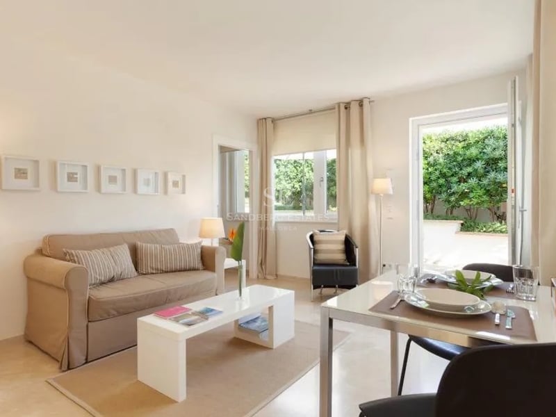 Salon contemporain aux tons crème avec coin repas s'ouvrant sur un jardin luxuriant.