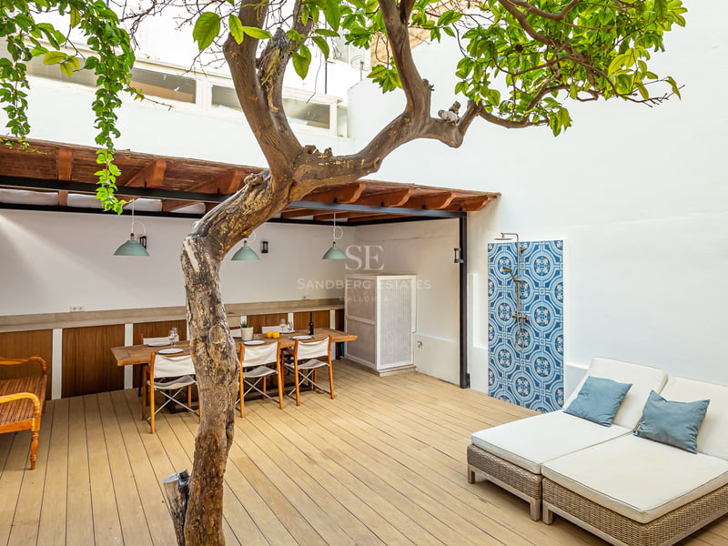 Terrasse en bois avec table à manger sous pergola, grand bain de soleil et douche extérieure carrelée de bleu.