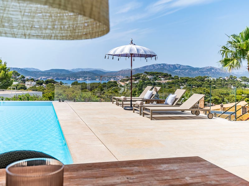 Vue d'une luxueuse villa moderne avec piscine à débordement, vastes terrasses et vue panoramique sur la mer. Design minimaliste et élégant.