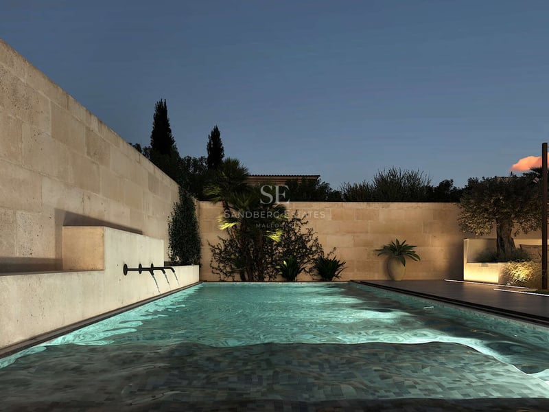 Piscine rectangulaire éclairée avec trois jets d'eau intégrés dans un mur en pierre naturelle au crépuscule.