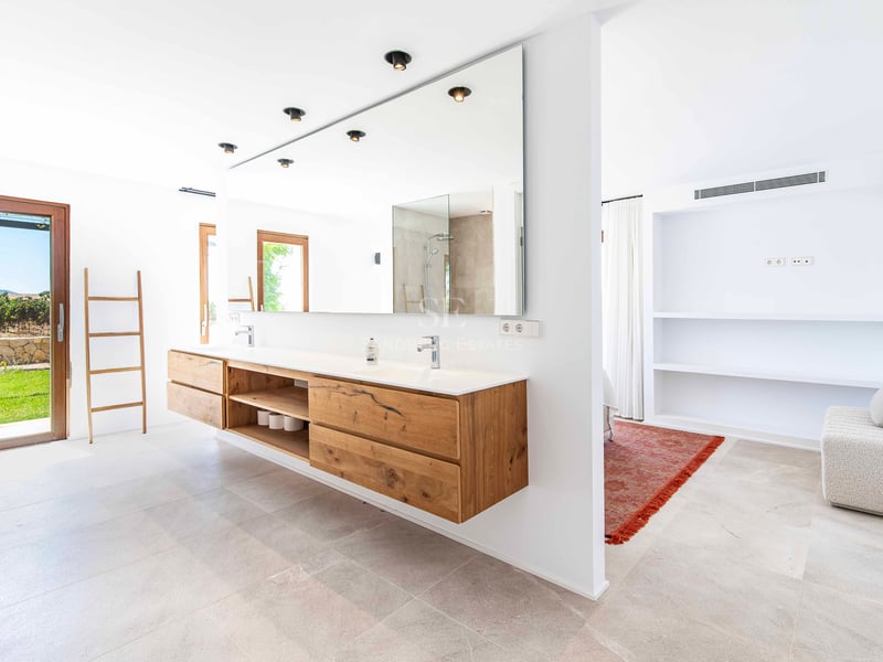 Grande salle de bain moderne avec meuble en chêne suspendu, grand miroir et accès direct au jardin.