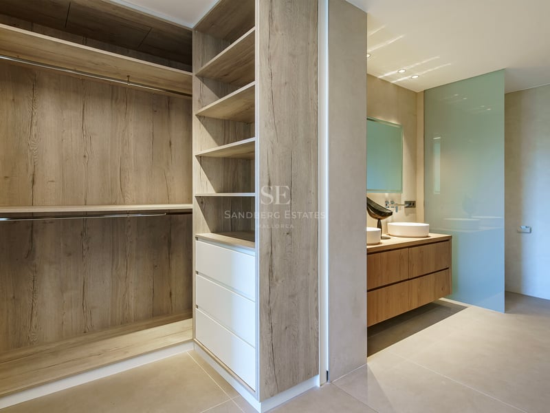 Dressing moderne avec menuiserie en chêne menant à une salle de bains avec double vasque et paroi en verre dépoli.