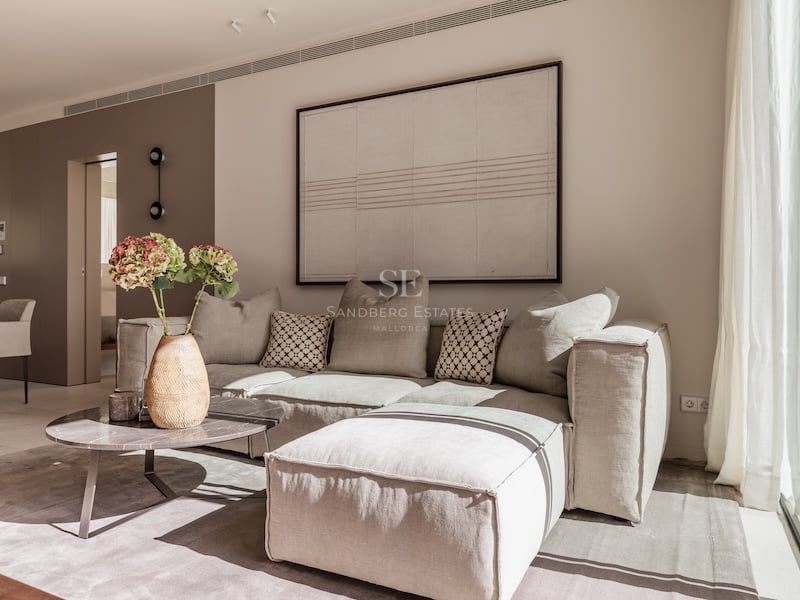 Salon minimaliste avec un grand canapé d'angle beige, une table basse en marbre et un grand tableau abstrait.