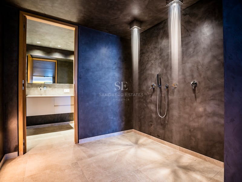 Douche à l'italienne moderne avec deux pommeaux de tête et murs en béton ciré anthracite.