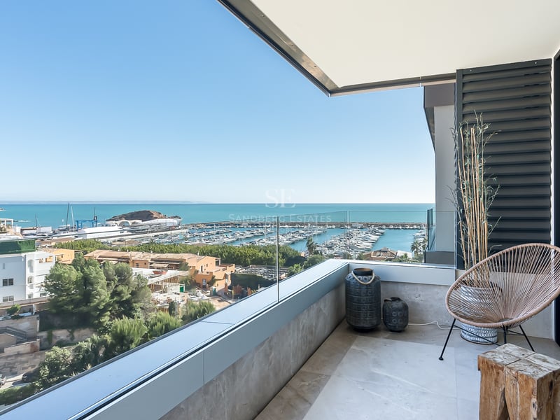 Terraza contemporánea con barandillas de cristal con vistas a un puerto deportivo y al mar Mediterráneo.