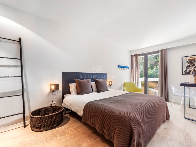 Chambre contemporaine avec lit double, parquet clair et porte vitrée ouvrant sur une terrasse.