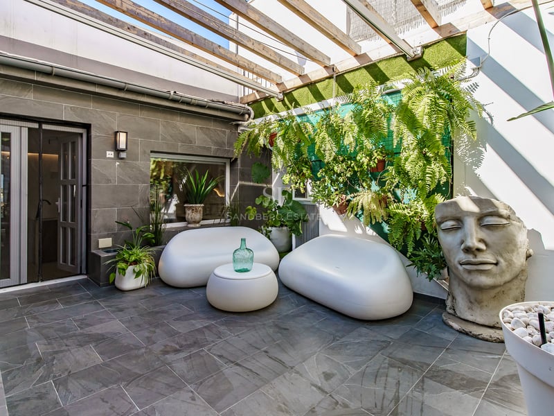 Patio contemporain avec canapés incurvés blancs, dalles en pierre, pergola en bois et une grande sculpture de visage.