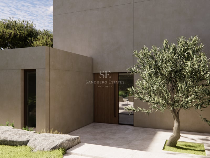 Entrée de villa moderne avec murs en béton beige, porte en bois et un olivier dans une cour en pierre.