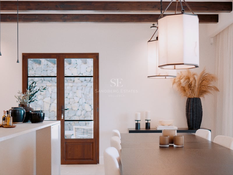 Vue intérieure d'une salle à manger moderne avec poutres en bois sombre, grande table et suspensions design.