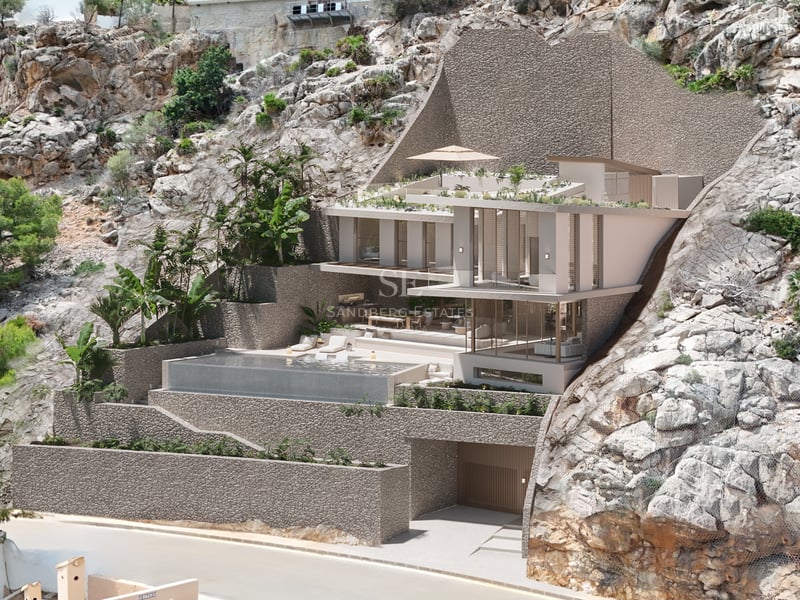 Villa moderne sur plusieurs niveaux intégrée dans une falaise avec piscine à débordement et baies vitrées.