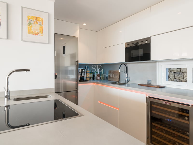 Cuisine contemporaine blanche avec placards sans poignées, cave à vin intégrée et appareils Siemens en acier inoxydable.