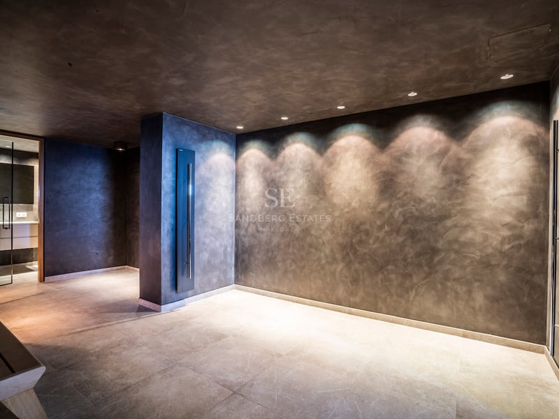 Espace spa minimaliste avec murs texturés sombres, éclairage par spots et sol en pierre naturelle.