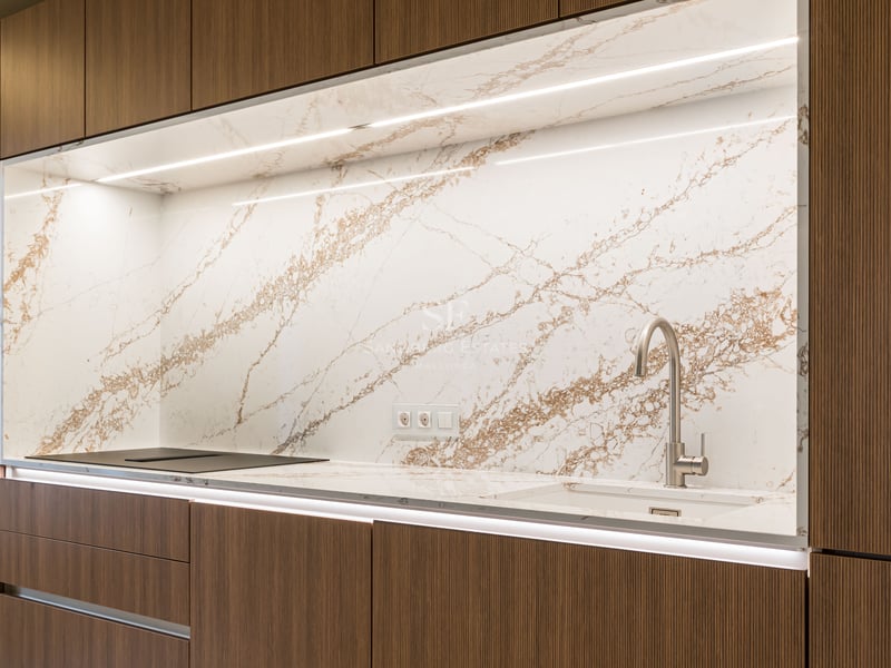 Modern kitchen featuring dark wood cabinetry, a marble backsplash with brown veining, and integrated LED lighting.