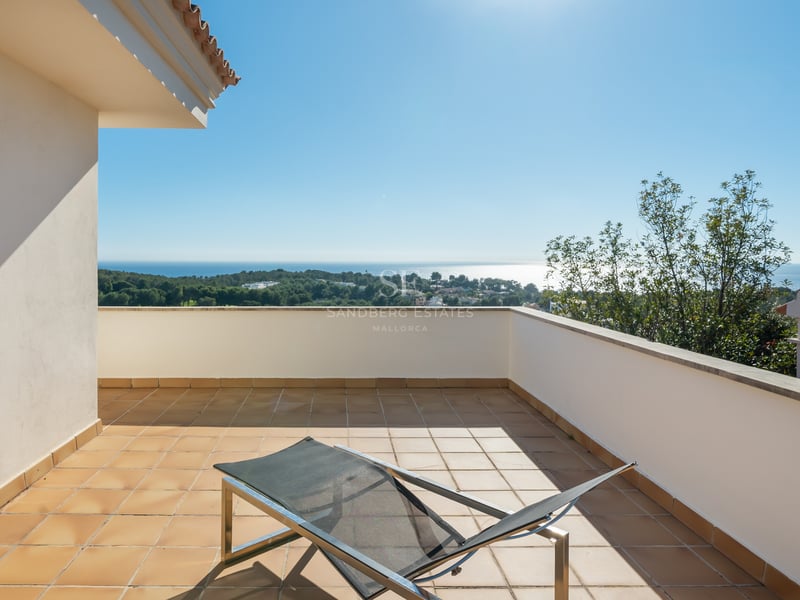 Terrasse ensoleillée avec carrelage en terre cuite et chaise longue moderne surplombant la côte et la mer Méditerranée.