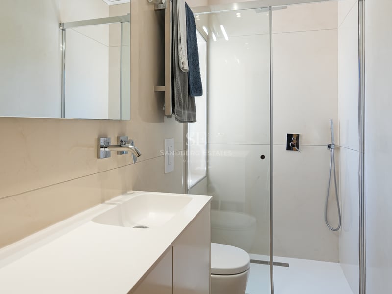Salle de bains contemporaine avec carrelage crème, paroi de douche en verre et robinetterie chromée.
