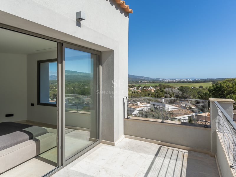 Terrasse privée en pierre naturelle avec baies vitrées coulissantes donnant sur une vallée verdoyante.