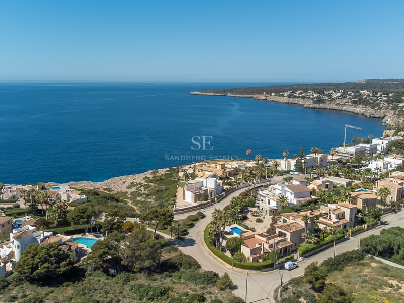 Vue aérienne de villas blanches de luxe avec piscines bleues le long d'une côte méditerranéenne rocheuse.