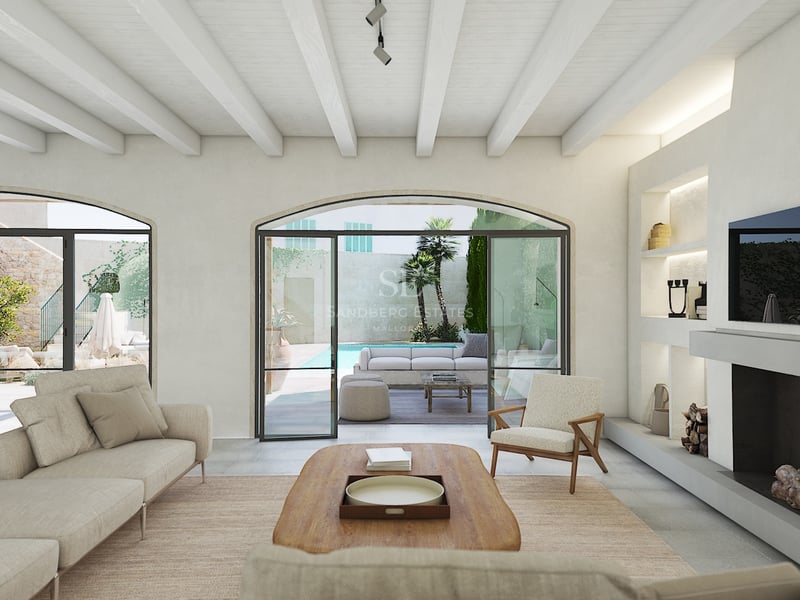 Salón elegante con techos de vigas blancas, chimenea y puertas arqueadas que dan a una piscina privada y terraza.
