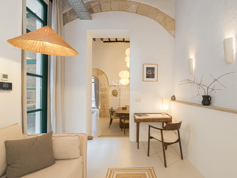Intérieur méditerranéen avec murs blancs, arche en pierre naturelle, bureau en bois et canapé en lin.